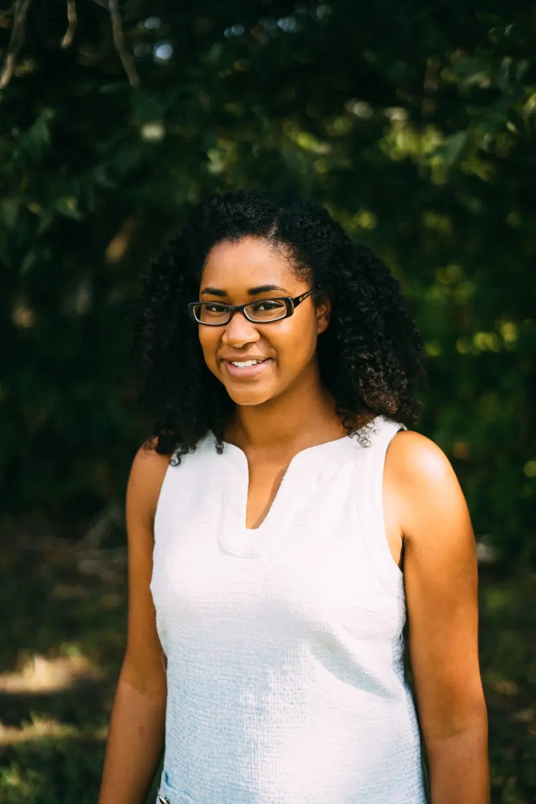 Dr. Allison J. McDade, MD, smiling in glasses in front of green trees