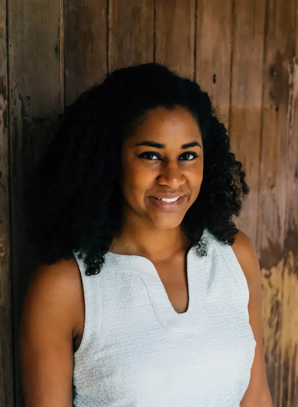 Dr. Allison J. McDade, MD, smiling against a weathered wood wall